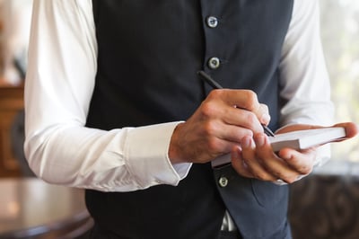 Waiter taking an order wearing a waistcoat in a fancy restaurant